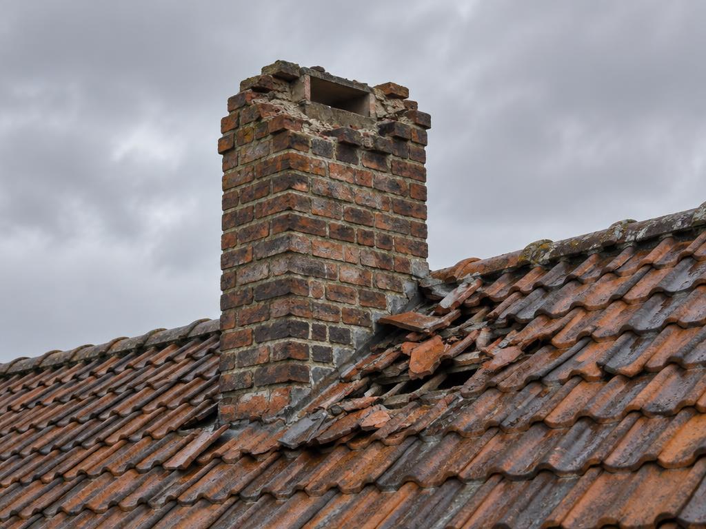 Schouw zonder blauwstenen deksteen met gebroken pannen na een storm, vóór herstelling door Merchiers Dak en Woningrenovatie